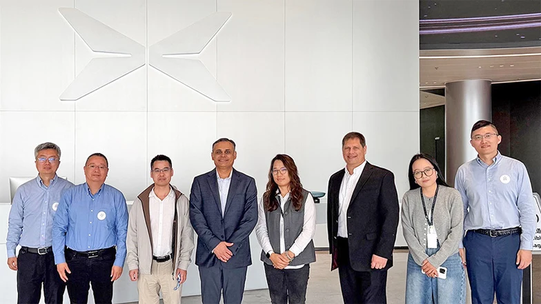 Group of 8 people in front of a large Xpeng logo on a white wall.