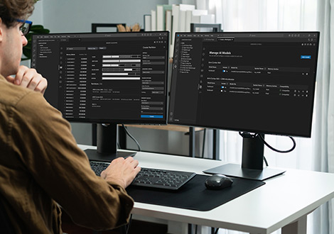 Person working at a dual-monitor setup displaying data management and software interface dashboards