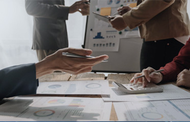 Team members working together at a desk with charts and graphs during a business meeting.