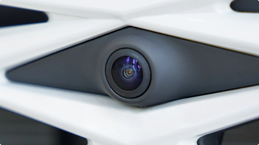 Close-up of ADAS camera lens on a white and black car.