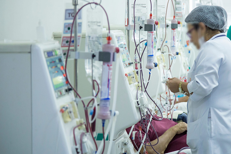 Nurse monitors patient undergoing dialysis treatment.