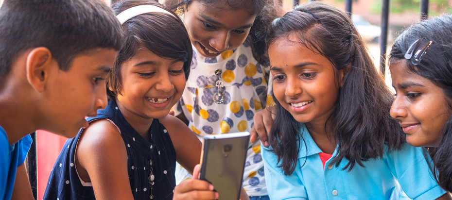 Group of young students in India looking at a mobile phone during a school break.