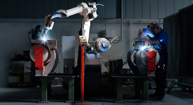 Cobot and welder working side-by-side in a dark room