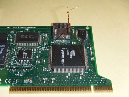 QFP品取り外し作業のための銅線セットアップを示す電子基板の画像。緑色の基板上に複数のICチップがあり、中央のQFPチップにはピラミッド状に組み合わせた細い銅線(7本のビニール単線)が取り付けられています。高難度のQFP品取り外し技術の重要なステップである銅線配置の具体例を示す専門的な技術写真です。